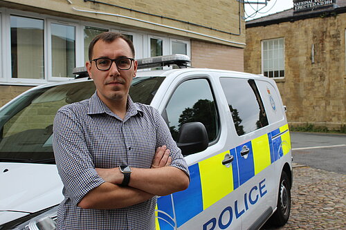 Tom Gordon MP in front of a police van with his arms folded
