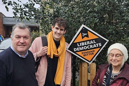 Josh Matthews with Chris Maines and a female Lib Dem activist in front of a Lib Dem diamond