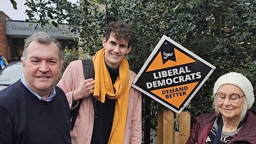 Josh Matthews with Chris Maines and a female Lib Dem activist in front of a Lib Dem diamond