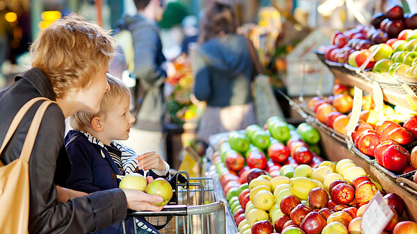 A mother and son picking which apple to buy.