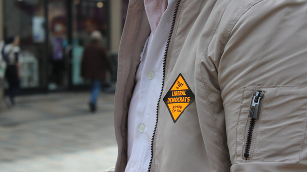 A person on a street showing a Liberal Democrat badge