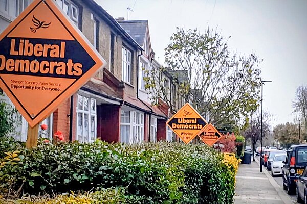 Photo of Lib Dem orange garden boards on a Haringey street