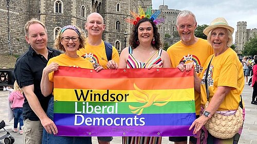 Mixed group of adults hold a pride banner outside Windsor Castle