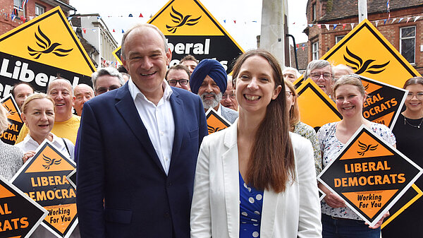 Ed Davey and Emma Holland-Lindsay in front of a crowd holding Lib Dem signs.