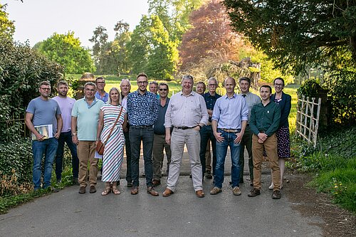 A group of around 16 people, including Adam Dance MP and Alistair Carmichael MP, standing outdoors on a tree-lined path during a sunny afternoon, gathered for a rural issues forum in Somerset.